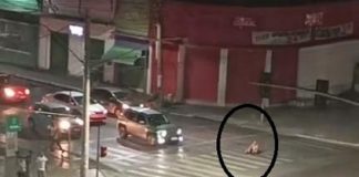 Uma mulher é flagrada sentada em uma faixa para pedestres em avenida movimentada da capital